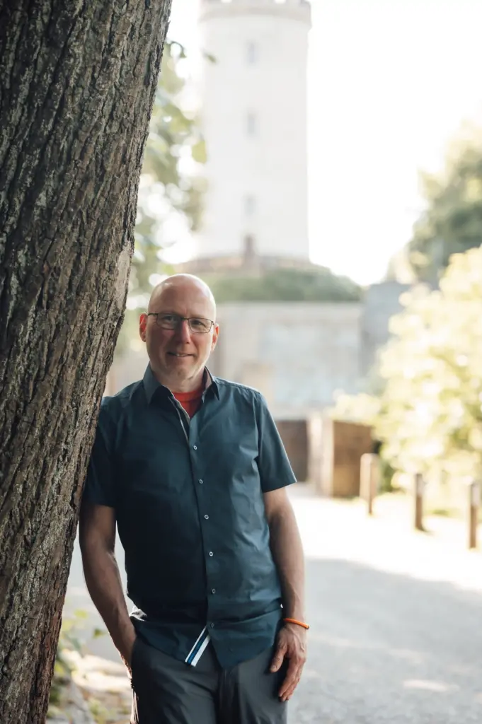 Jörn Kornfeld, Coach bei Trennung und Beziehungskrisen – Portrait von ihm an einen Baum gelehnt in einer ruhigen Naturlandschaft