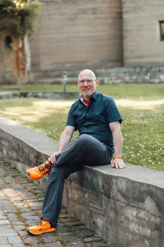 Jörn Kornfeld, Coach für Trennung, Scheidung und Beziehungskrisen, sitzt lächelnd im Freien.
